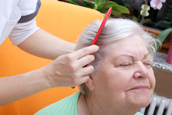 elder lady having her hair brushed by a care giver